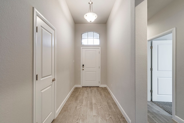 doorway to outside featuring baseboards and light wood finished floors