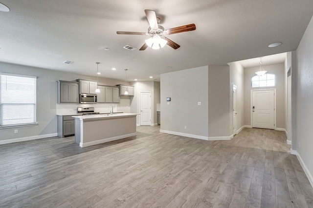 kitchen with visible vents, gray cabinetry, a center island with sink, light wood-type flooring, and stainless steel appliances