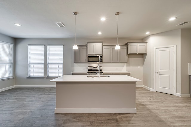 kitchen with visible vents, gray cabinetry, stainless steel appliances, and a sink