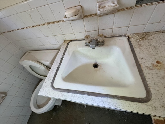 bathroom with a sink, toilet, and tile walls