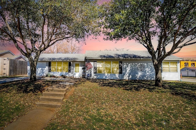 ranch-style home with a front lawn, an attached garage, and fence