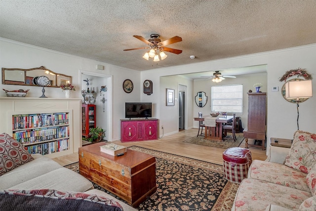 living room featuring a ceiling fan, crown molding, wood finished floors, and a textured ceiling