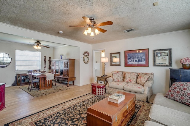 living area featuring visible vents, wood finished floors, and crown molding