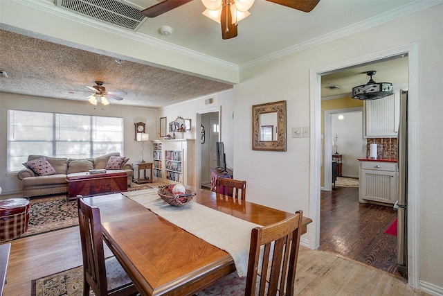 dining area featuring visible vents, crown molding, ceiling fan, hardwood / wood-style flooring, and a textured ceiling