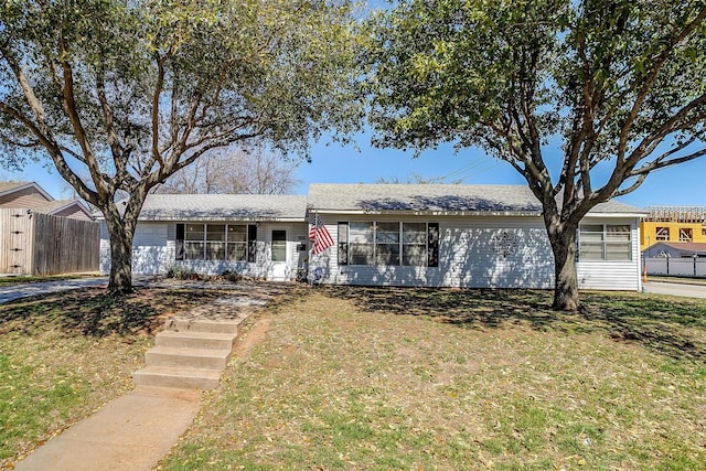 ranch-style house featuring a front lawn, fence, and a garage