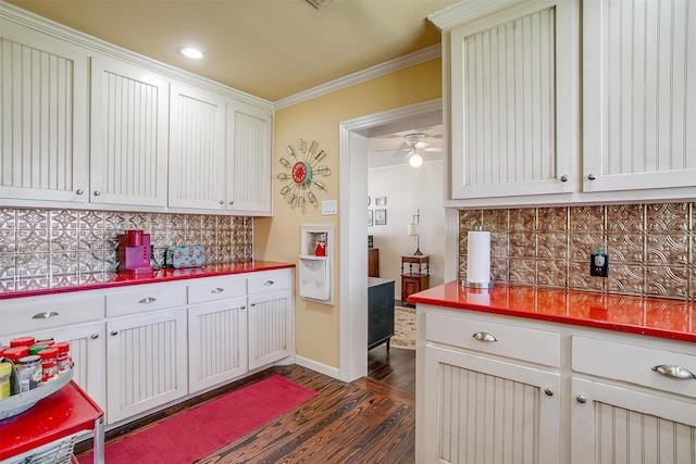 kitchen with dark wood-type flooring, backsplash, ornamental molding, and white cabinetry