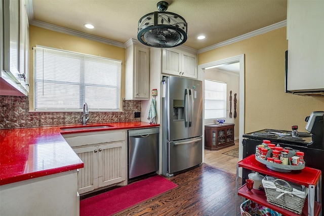 kitchen featuring wood finished floors, ornamental molding, stainless steel appliances, and a sink