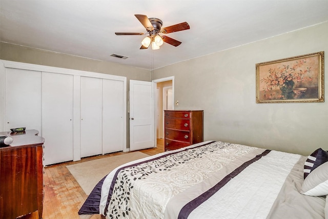 bedroom with a closet, visible vents, light wood-style flooring, and ceiling fan