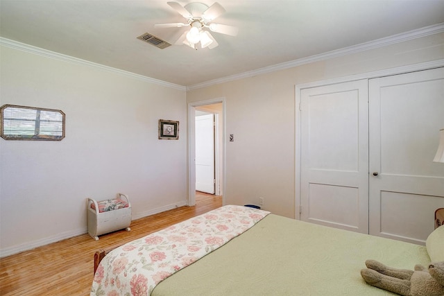 bedroom featuring visible vents, baseboards, ornamental molding, light wood-style flooring, and a closet