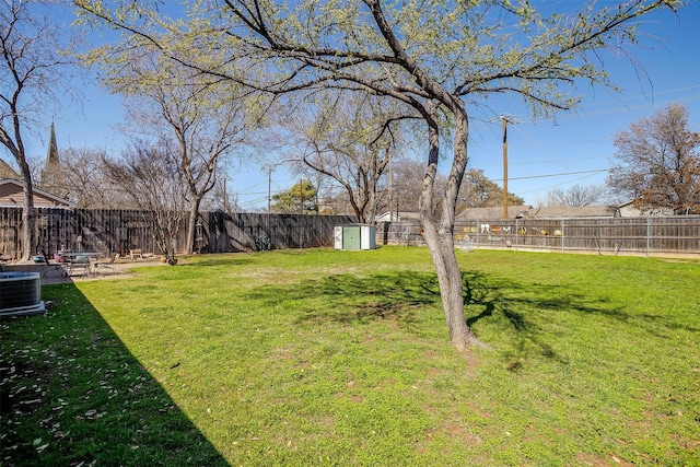 view of yard with an outbuilding, a shed, central AC unit, and a fenced backyard