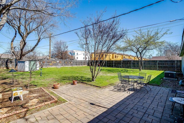 view of patio featuring an outbuilding, a fenced backyard, a storage shed, a garden, and central AC unit