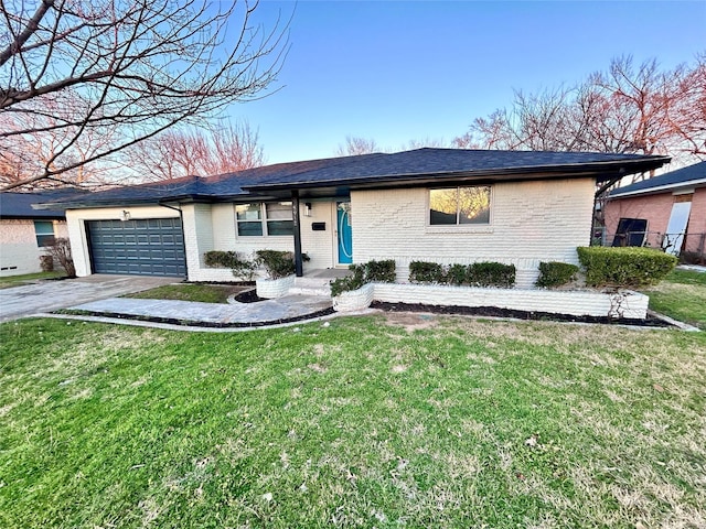 ranch-style home featuring driveway, an attached garage, a shingled roof, a front lawn, and brick siding