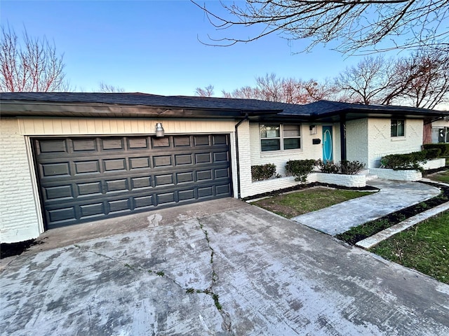 single story home featuring concrete driveway, an attached garage, and brick siding