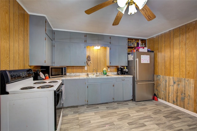 kitchen with a sink, stainless steel appliances, wood walls, and gray cabinets