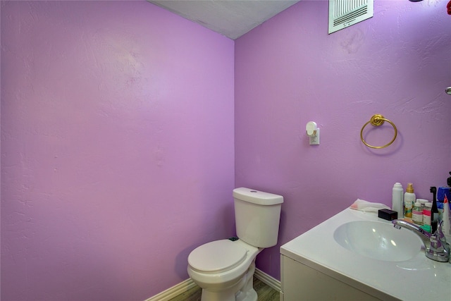 bathroom with visible vents, baseboards, toilet, wood finished floors, and vanity