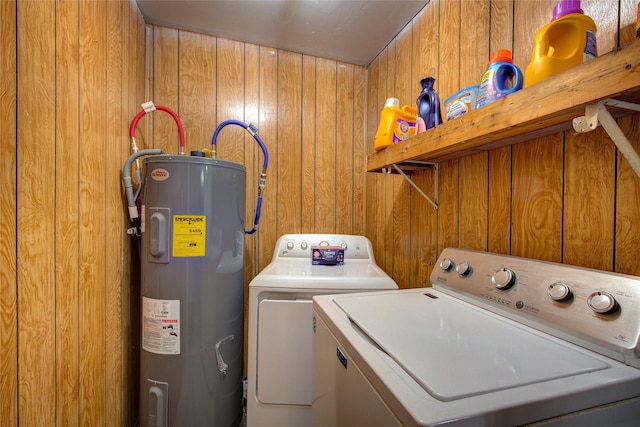 clothes washing area with laundry area, electric water heater, wooden walls, and washing machine and clothes dryer