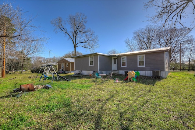 rear view of property with a playground, cooling unit, a yard, and metal roof