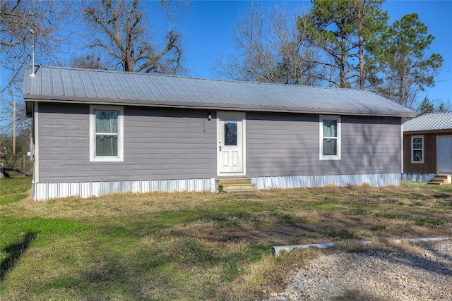 manufactured / mobile home with entry steps, metal roof, and a front lawn