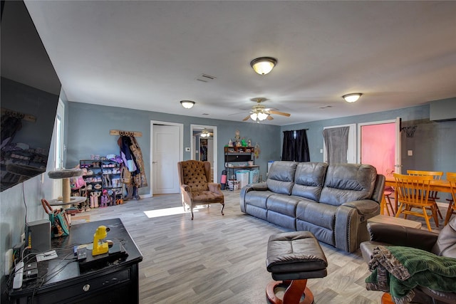 living area featuring light wood finished floors, visible vents, and ceiling fan