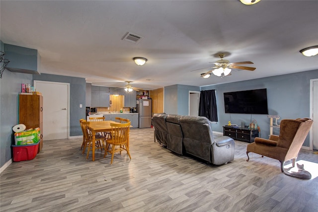 living room featuring visible vents, baseboards, light wood-type flooring, and ceiling fan