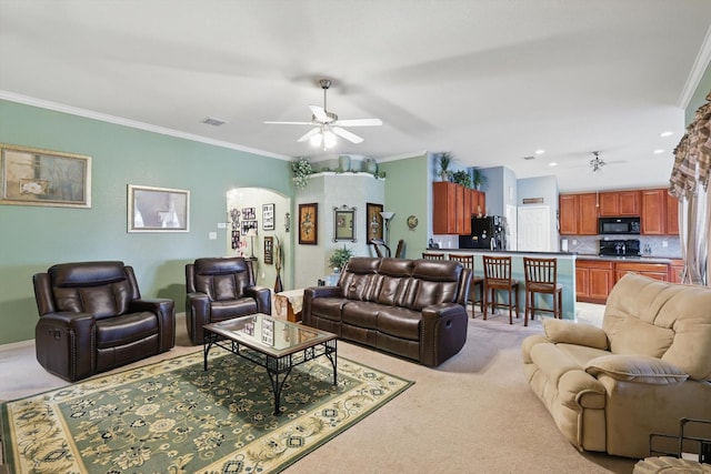 living area with a ceiling fan, light colored carpet, visible vents, and ornamental molding