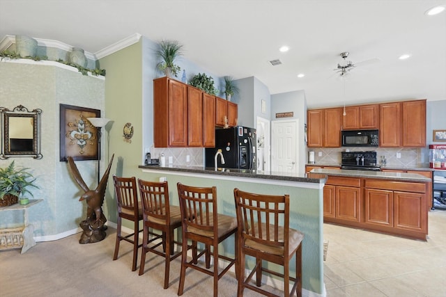 kitchen with visible vents, backsplash, ornamental molding, a peninsula, and black appliances