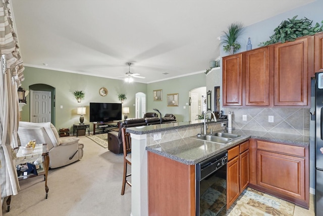 kitchen featuring a kitchen bar, a sink, arched walkways, a peninsula, and dishwasher