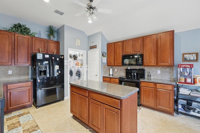 kitchen featuring light tile patterned floors, visible vents, black appliances, vaulted ceiling, and washing machine and dryer