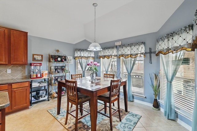 dining space with baseboards, light tile patterned flooring, and vaulted ceiling