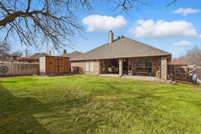 rear view of house featuring a patio, an outbuilding, a fenced backyard, and a shed