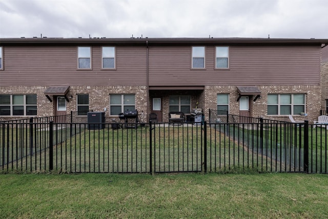 rear view of property featuring a yard, central AC unit, and brick siding