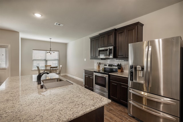 kitchen featuring visible vents, a sink, tasteful backsplash, appliances with stainless steel finishes, and dark brown cabinets