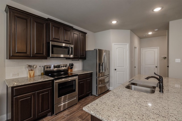 kitchen with wood finish floors, a sink, decorative backsplash, stainless steel appliances, and dark brown cabinets