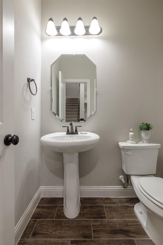 bathroom featuring baseboards, toilet, and wood tiled floor