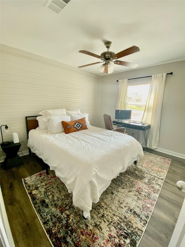 bedroom with ceiling fan, visible vents, baseboards, and wood finished floors