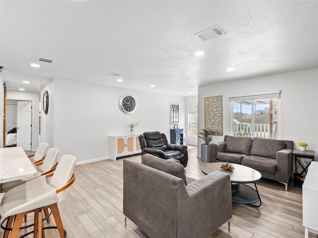 living area featuring visible vents, a textured ceiling, and light wood-style flooring