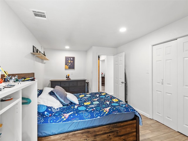 bedroom with recessed lighting, light wood-type flooring, visible vents, and a closet