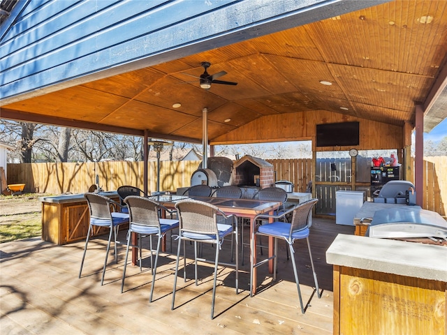 view of patio featuring a wooden deck, outdoor dining area, a ceiling fan, and fence