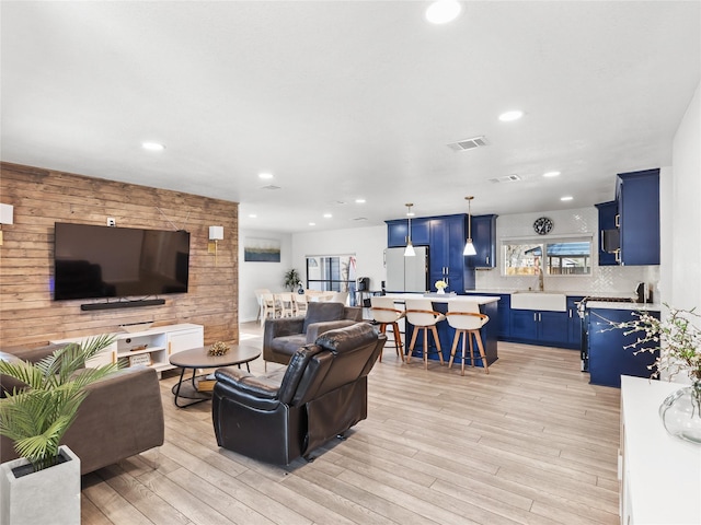 living area featuring recessed lighting, visible vents, light wood-style flooring, and wooden walls