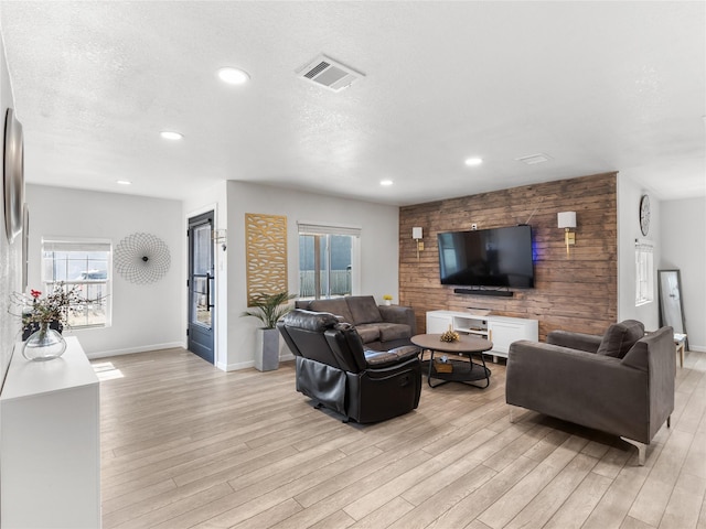 living room with a textured ceiling, recessed lighting, visible vents, and light wood-type flooring