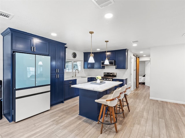 kitchen featuring a barn door, blue cabinetry, visible vents, and refrigerator with glass door