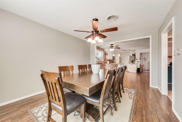 dining space with wood finished floors, visible vents, and baseboards