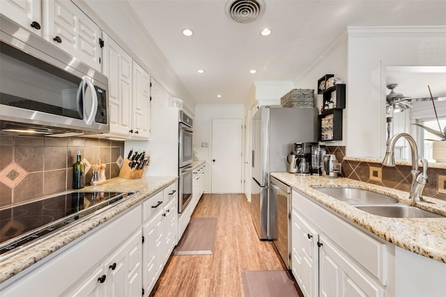 kitchen featuring visible vents, a sink, stainless steel appliances, white cabinets, and light wood finished floors