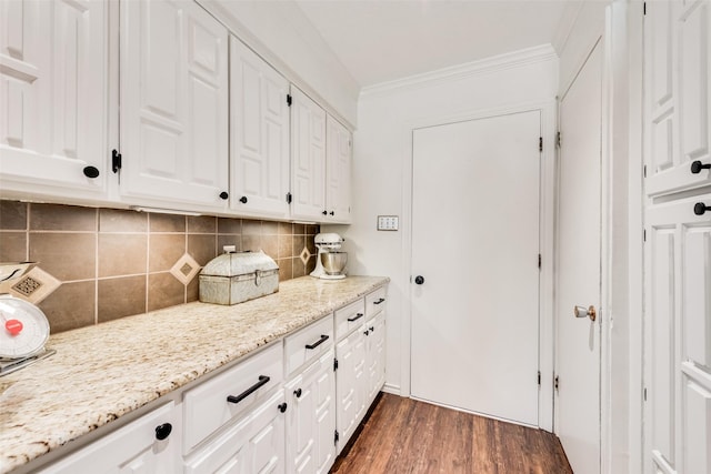 kitchen featuring dark wood finished floors, crown molding, light stone counters, and white cabinetry