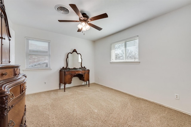 interior space with baseboards, light colored carpet, visible vents, and ceiling fan