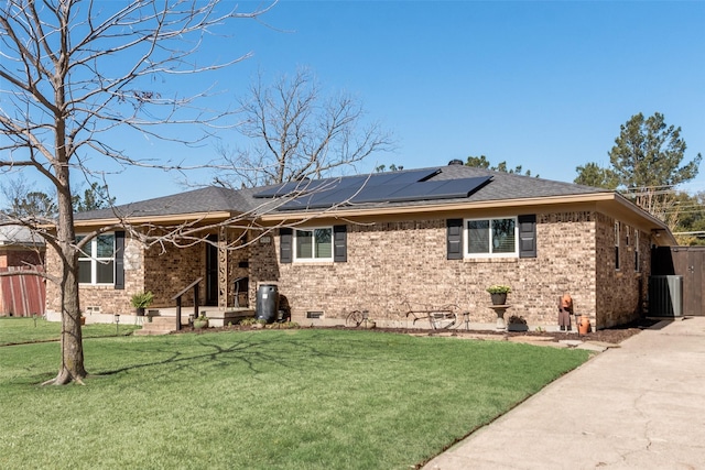 exterior space with fence, solar panels, a yard, crawl space, and brick siding