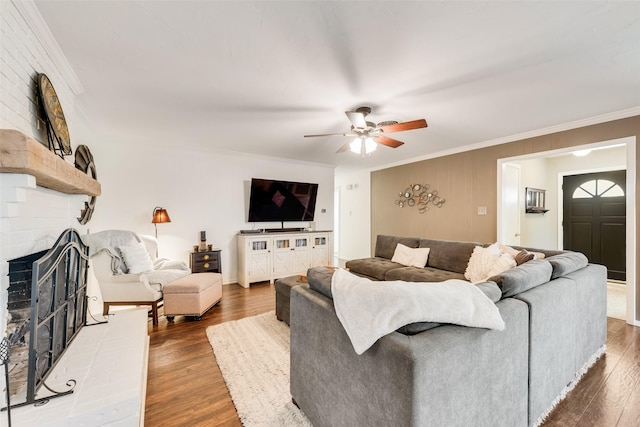 living area with crown molding, a brick fireplace, and wood finished floors