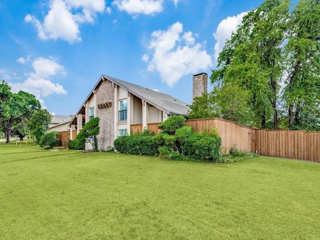 view of side of property featuring a yard, fence, and a chimney