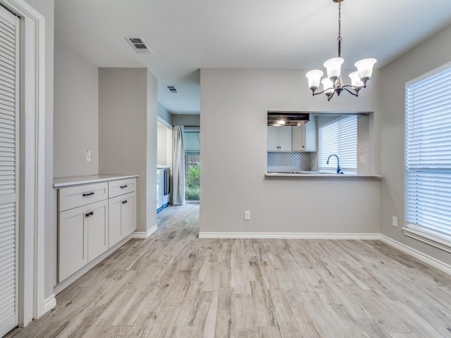 unfurnished dining area with visible vents, baseboards, a chandelier, and light wood finished floors