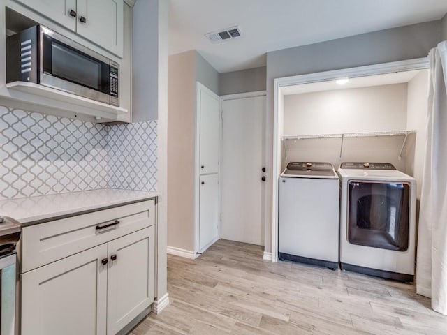 laundry area featuring light wood-style flooring, visible vents, and washer and clothes dryer